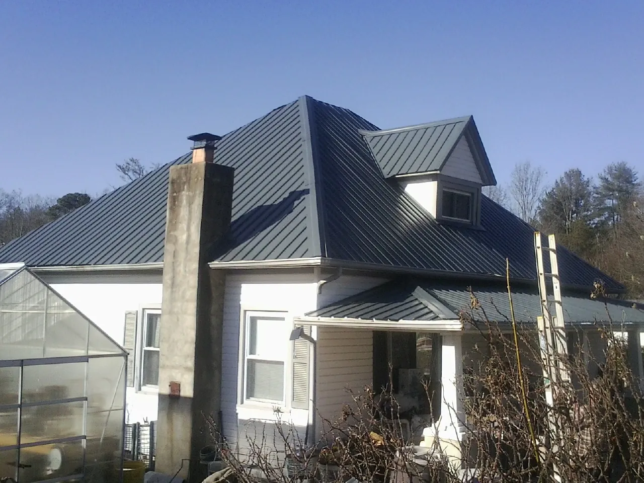 Dark blue standing seam metal roof on a white farmhouse with dormer — Slate & Tile Roof Repair by Roofing Brothers in Wood Ridge