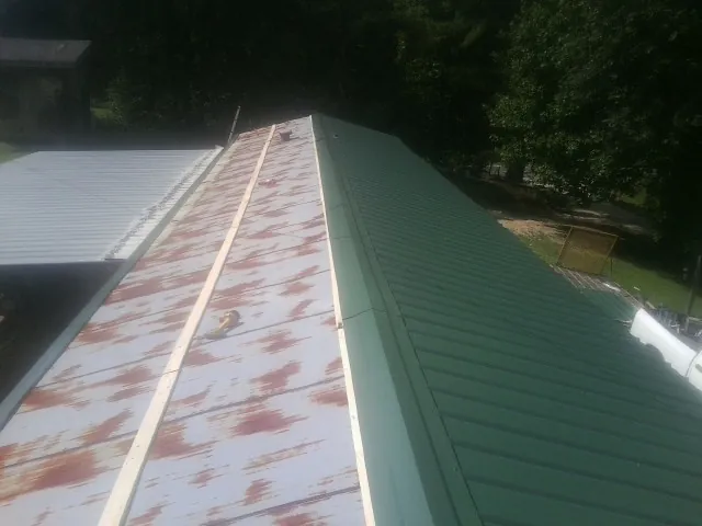 Old rusted panels beside newly installed green metal roofing — Wind Damage Roof Repair by Roofing Brothers in Wood Ridge