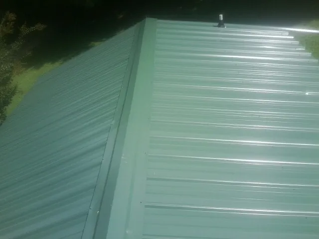 New green metal panels meeting at the ridge of a roof — Flat Roof Repair work by our crew in Wood Ridge