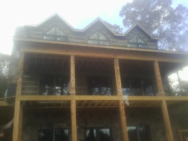 Dormers and porch framing on a large log home under construction — Roof Coating work by our crew in Wood Ridge