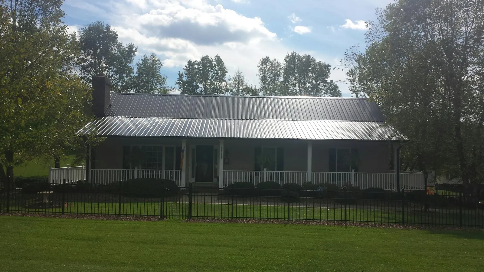 Gray metal roof on a brick ranch with a full width front porch — Gutter Guard Installation work by our crew in Wood Ridge