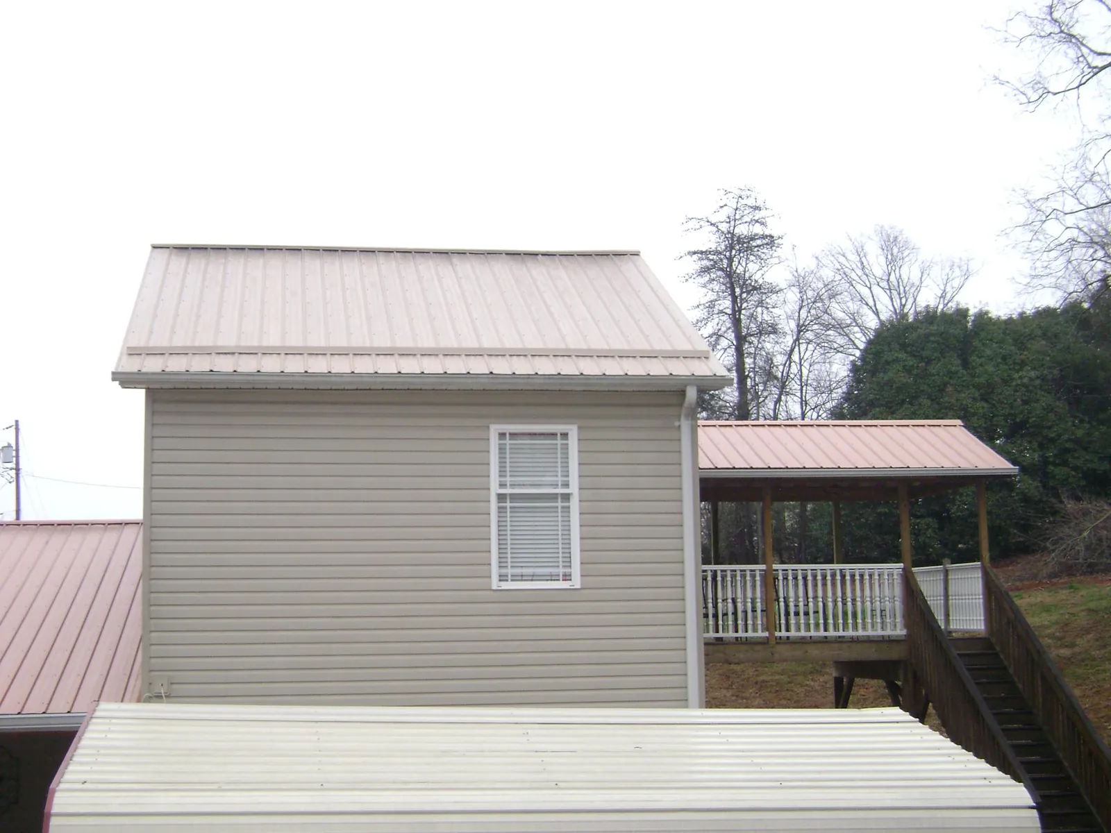 Tan metal roofs on a two story addition and attached porch, from a Roof Replacement job in Wood Ridge