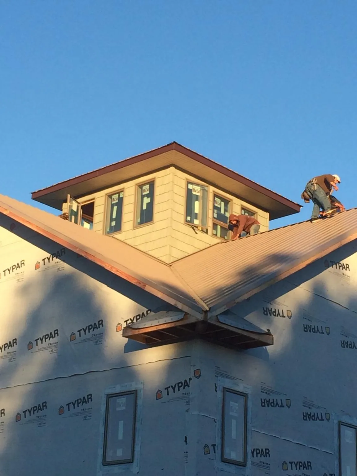 Roofers working around a rooftop cupola on a new metal roof at sunset — Roof Waterproofing in Wood Ridge by Roofing Brothers